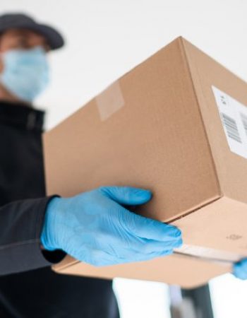Home delivery shopping box man wearing gloves and protective mask delivering packages at door.